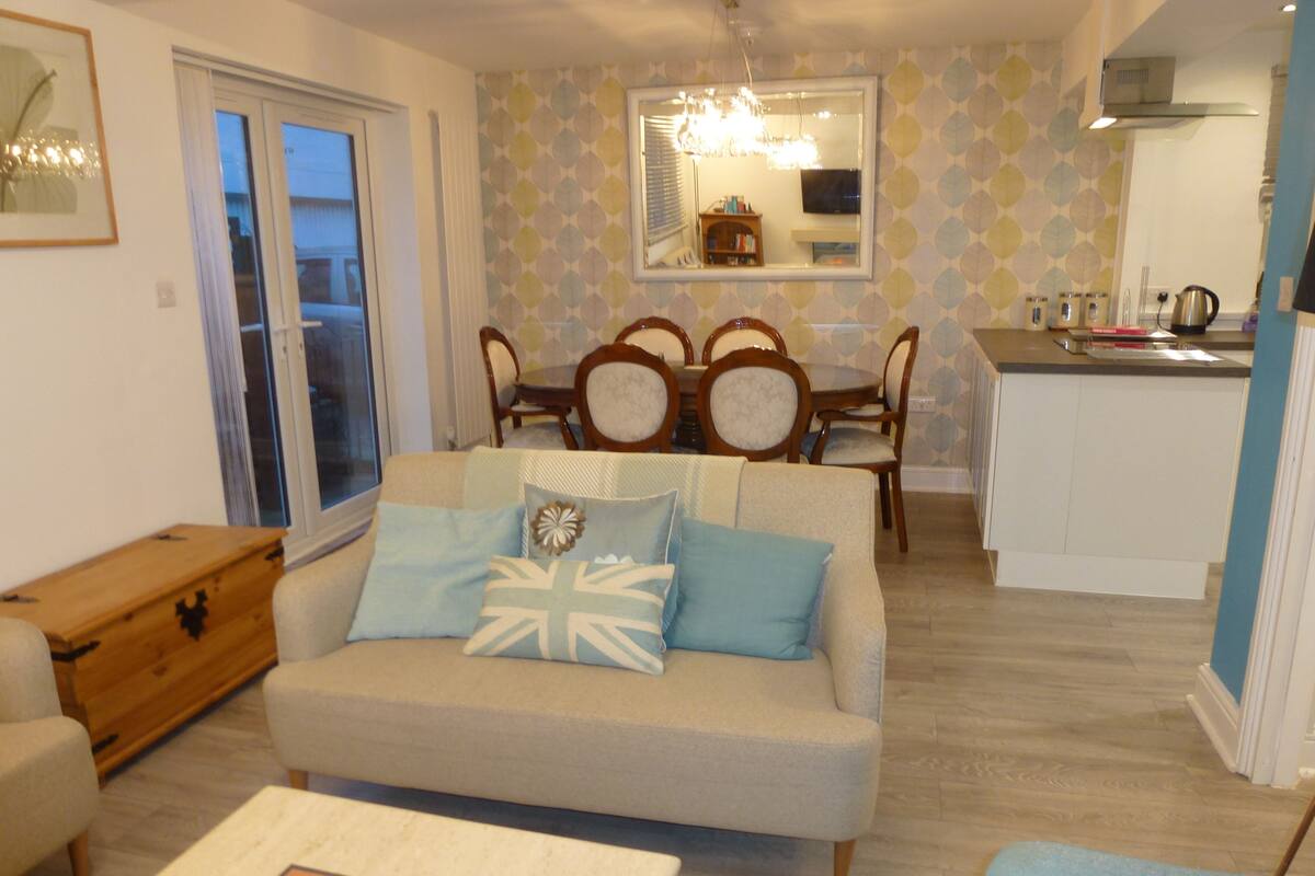 A living room with a sofa, a wooden side table, and a dining area with a table and chairs.