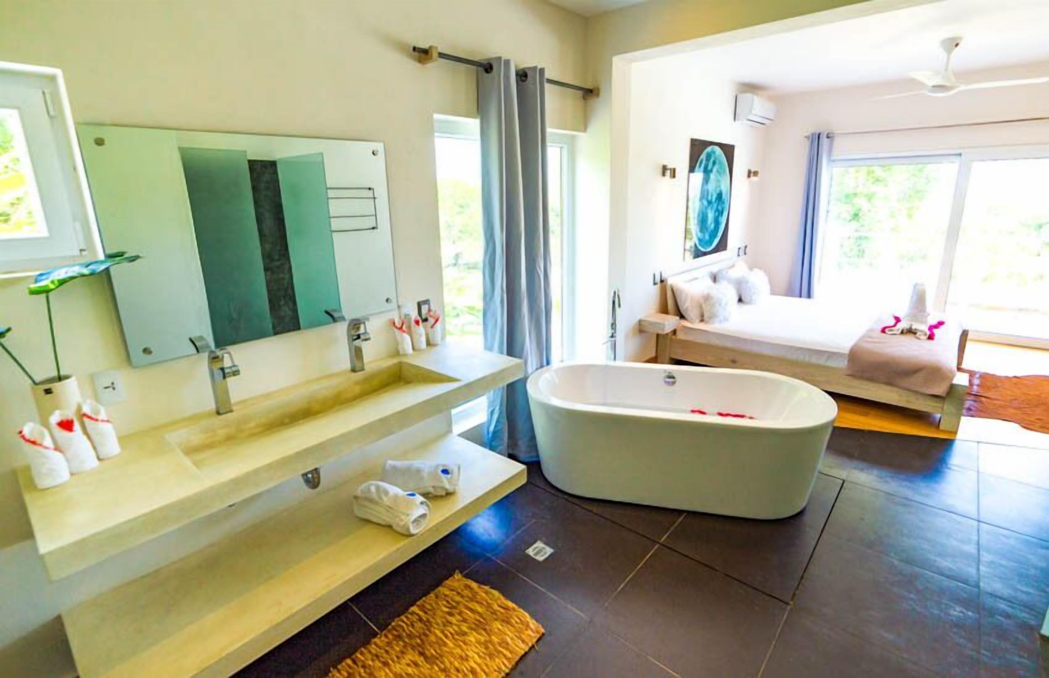 A modern bathroom with a freestanding bathtub, a large mirror, and a vanity with a sink.