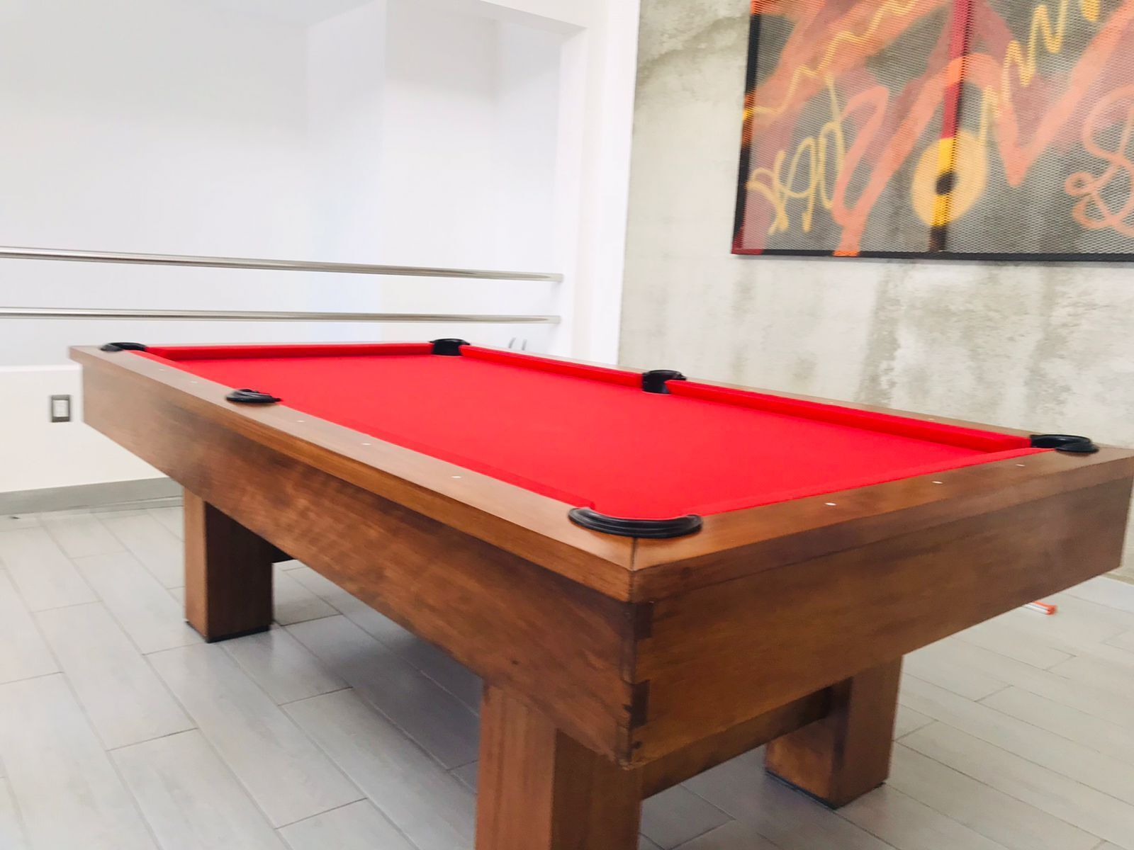 Une table de billard recouverte d’un feutre rouge, dotée d’un cadre en bois et de trous d’angle noirs.