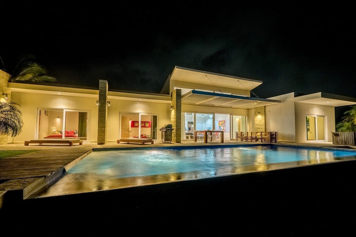 Une maison moderne dotée d’une piscine, d’un patio couvert et d’un coin repas.