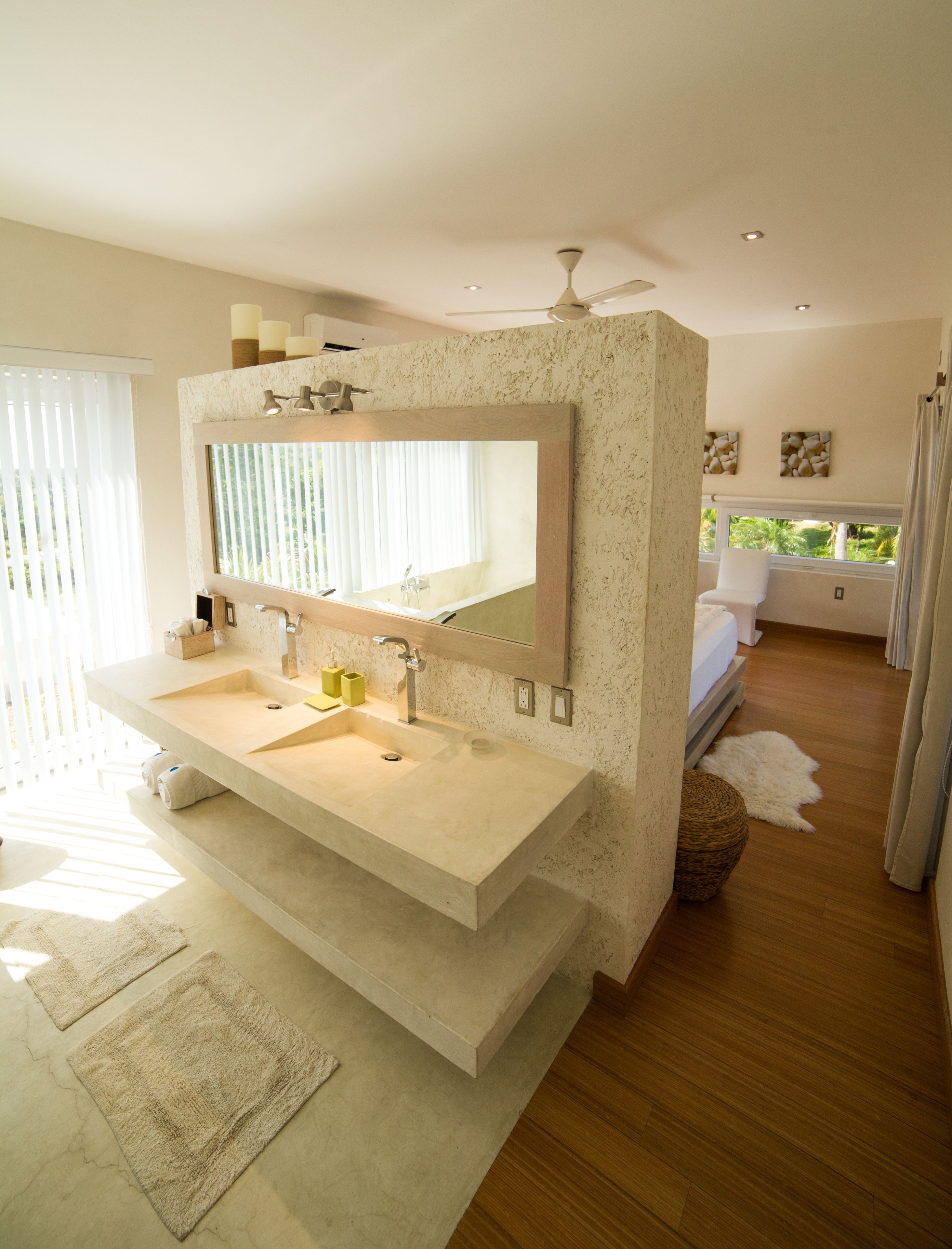 A modern bathroom with a large mirror, two sinks, and a ceiling fan.