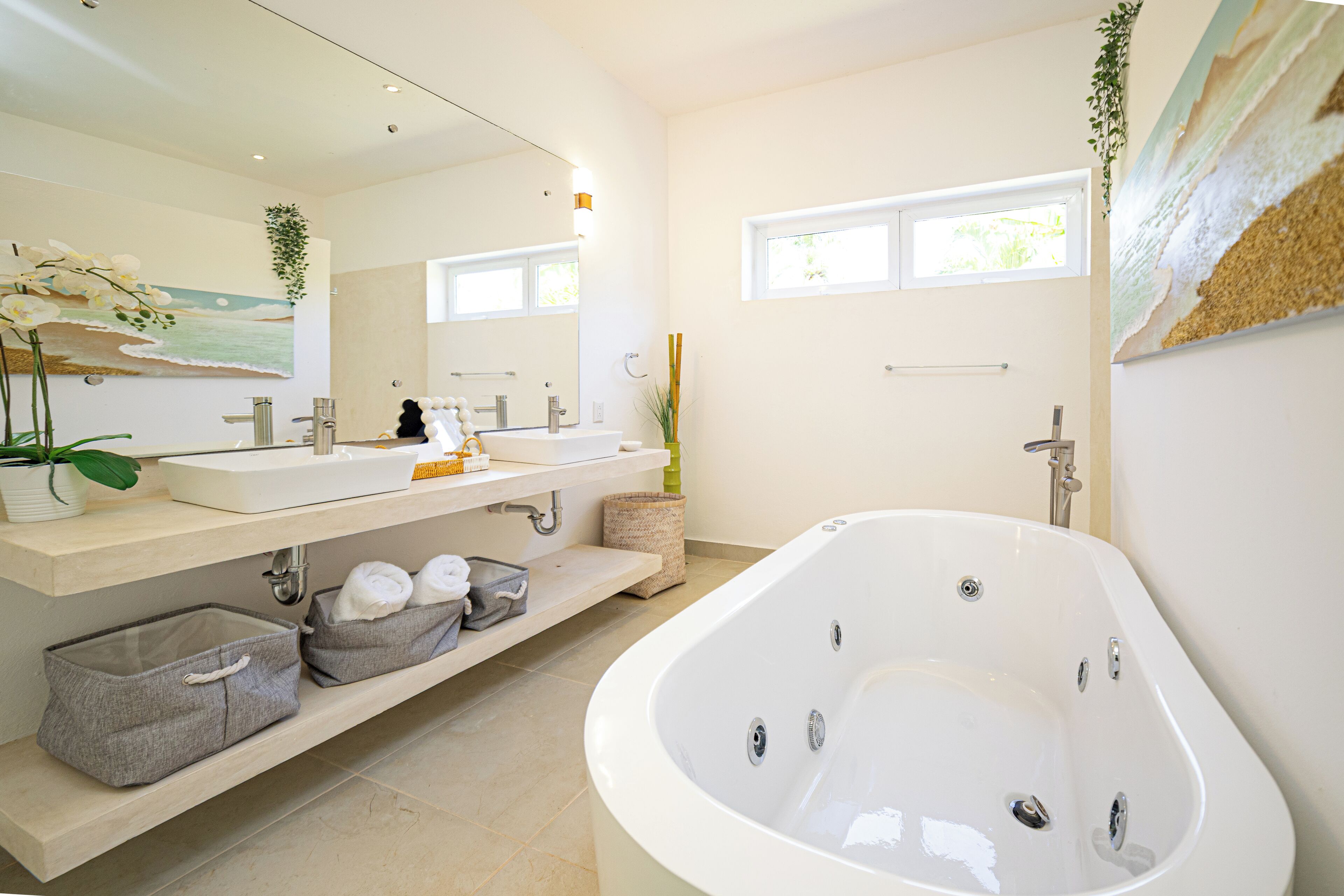Une salle de bain moderne avec une grande baignoire, deux lavabos et un miroir.