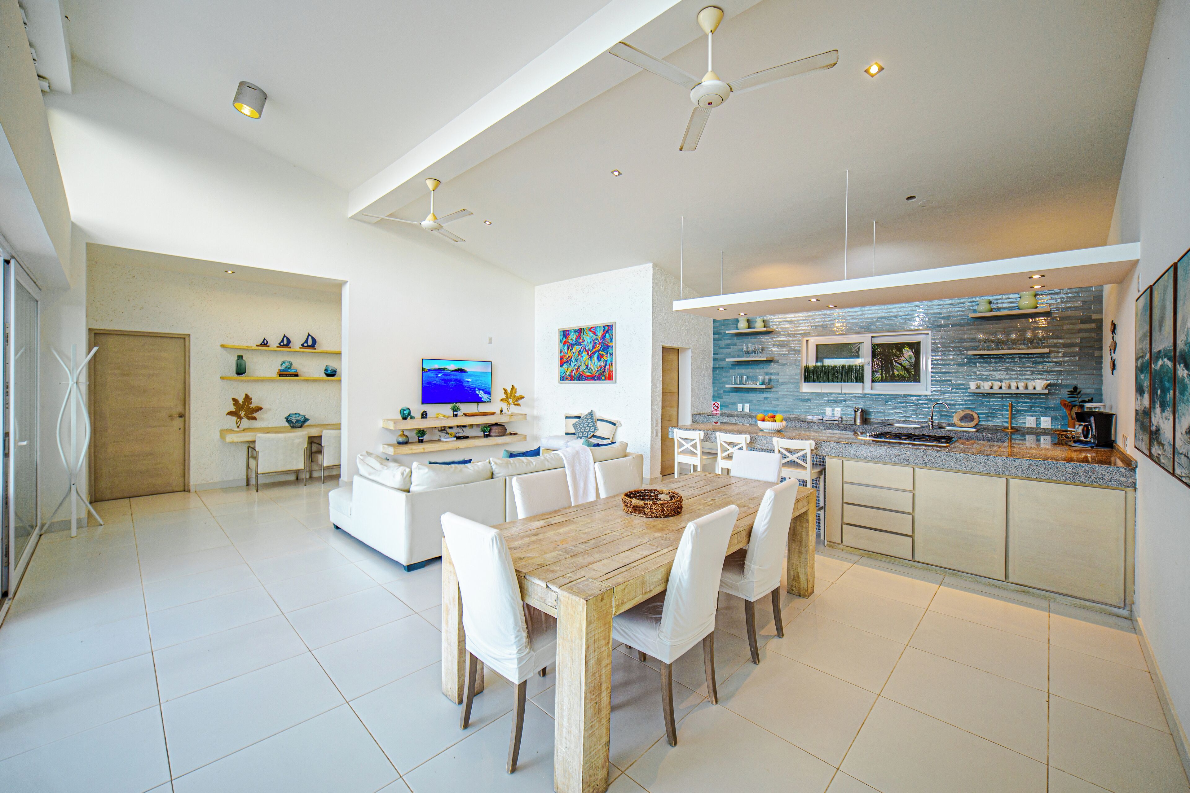 A modern kitchen with white cabinets, a wooden dining table, and a large island with seating.