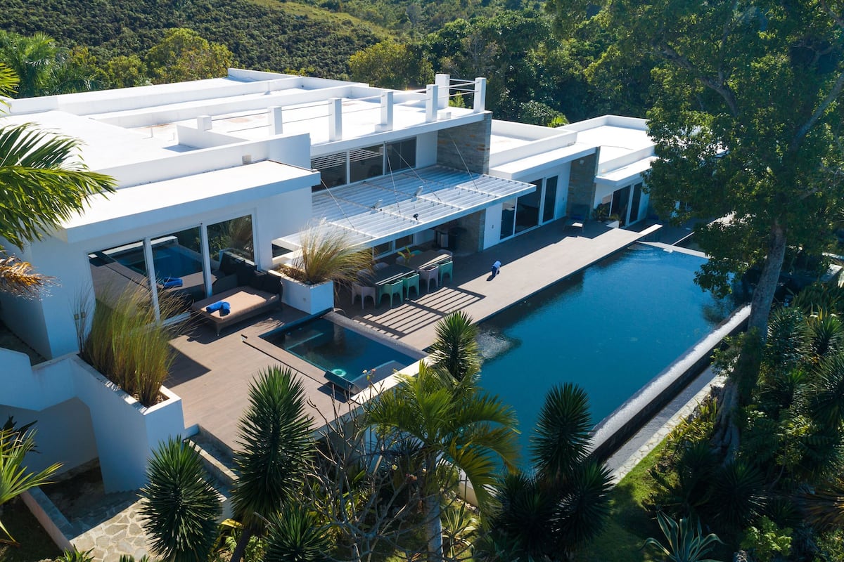 Une maison moderne dotée d’une piscine, entourée d’une végétation luxuriante.
