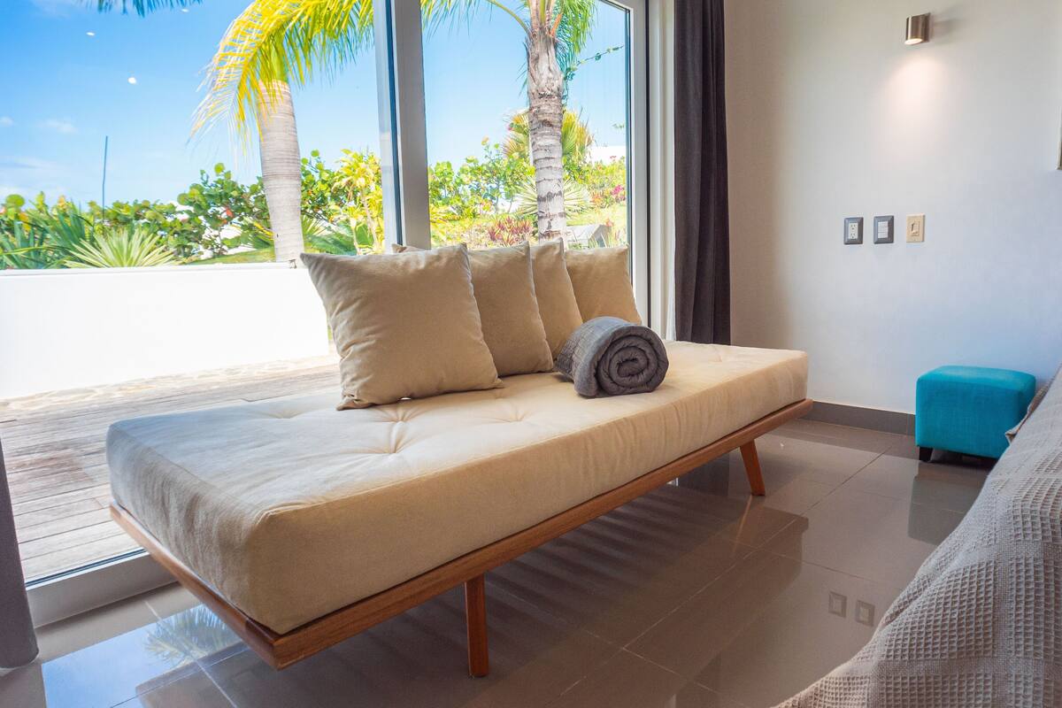 Une chambre moderne avec un lit, des oreillers et une vue sur des palmiers et la végétation environnante.