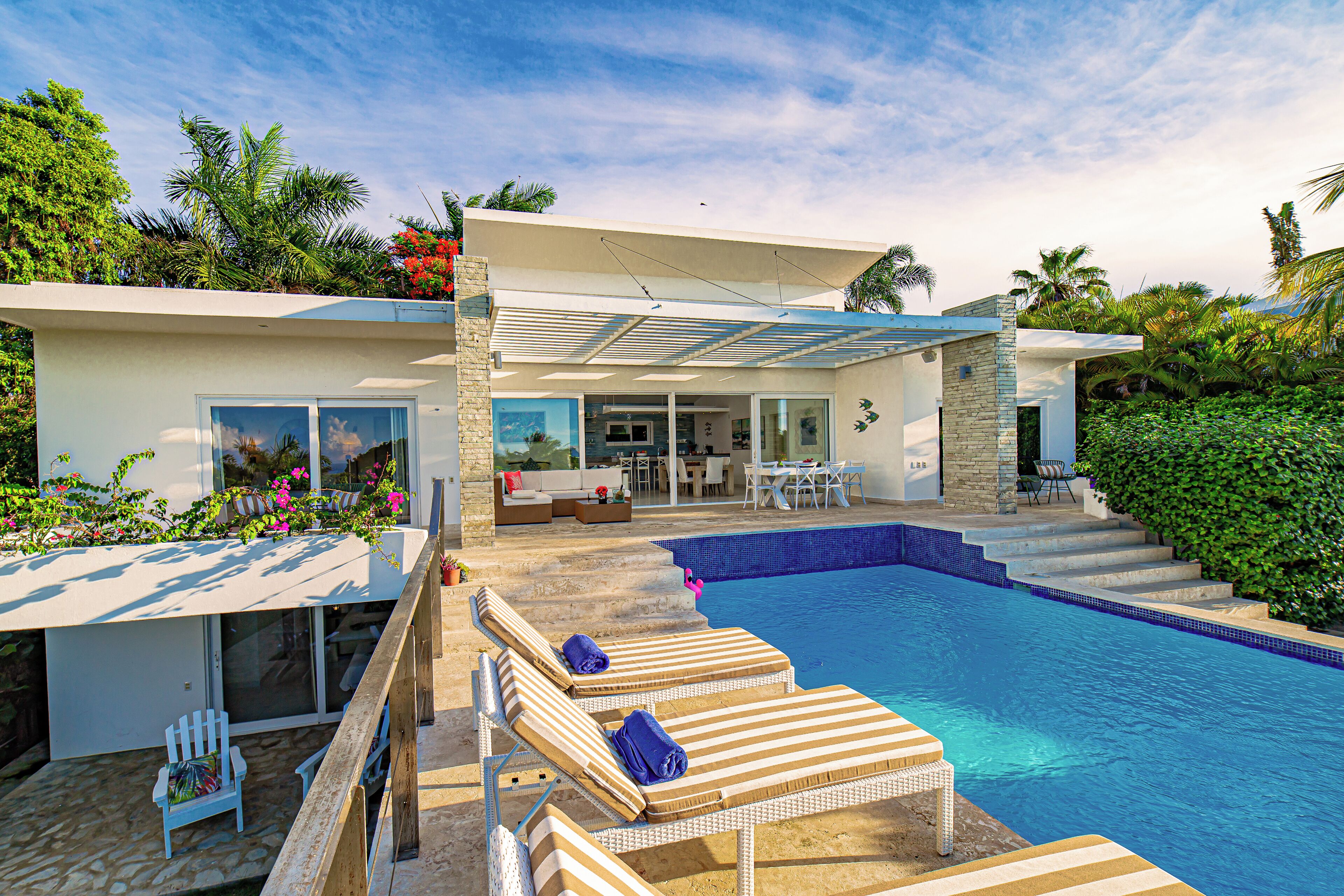 A modern house with a swimming pool, outdoor seating, and lush greenery.