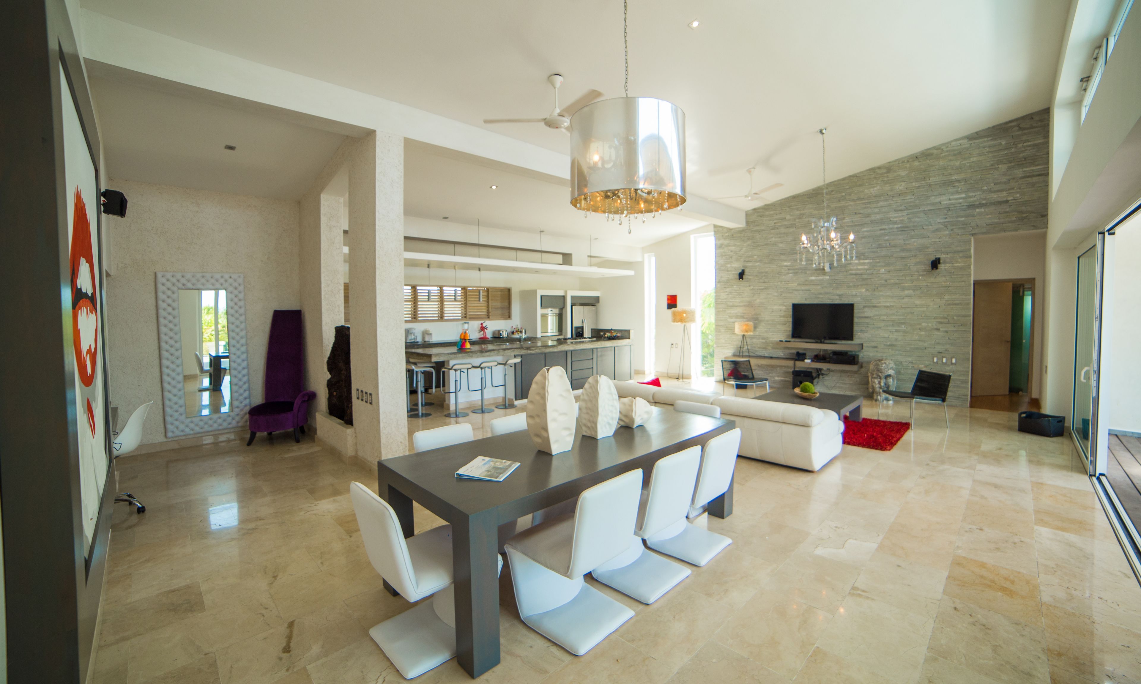 A spacious living area with a dining table, sofas, and a kitchen in the background.