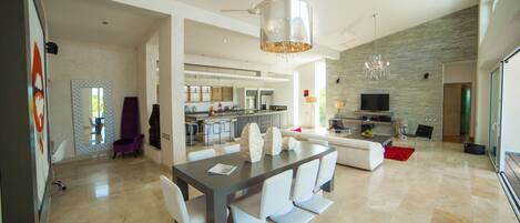 A spacious living area with a dining table, sofas, and a kitchen in the background.