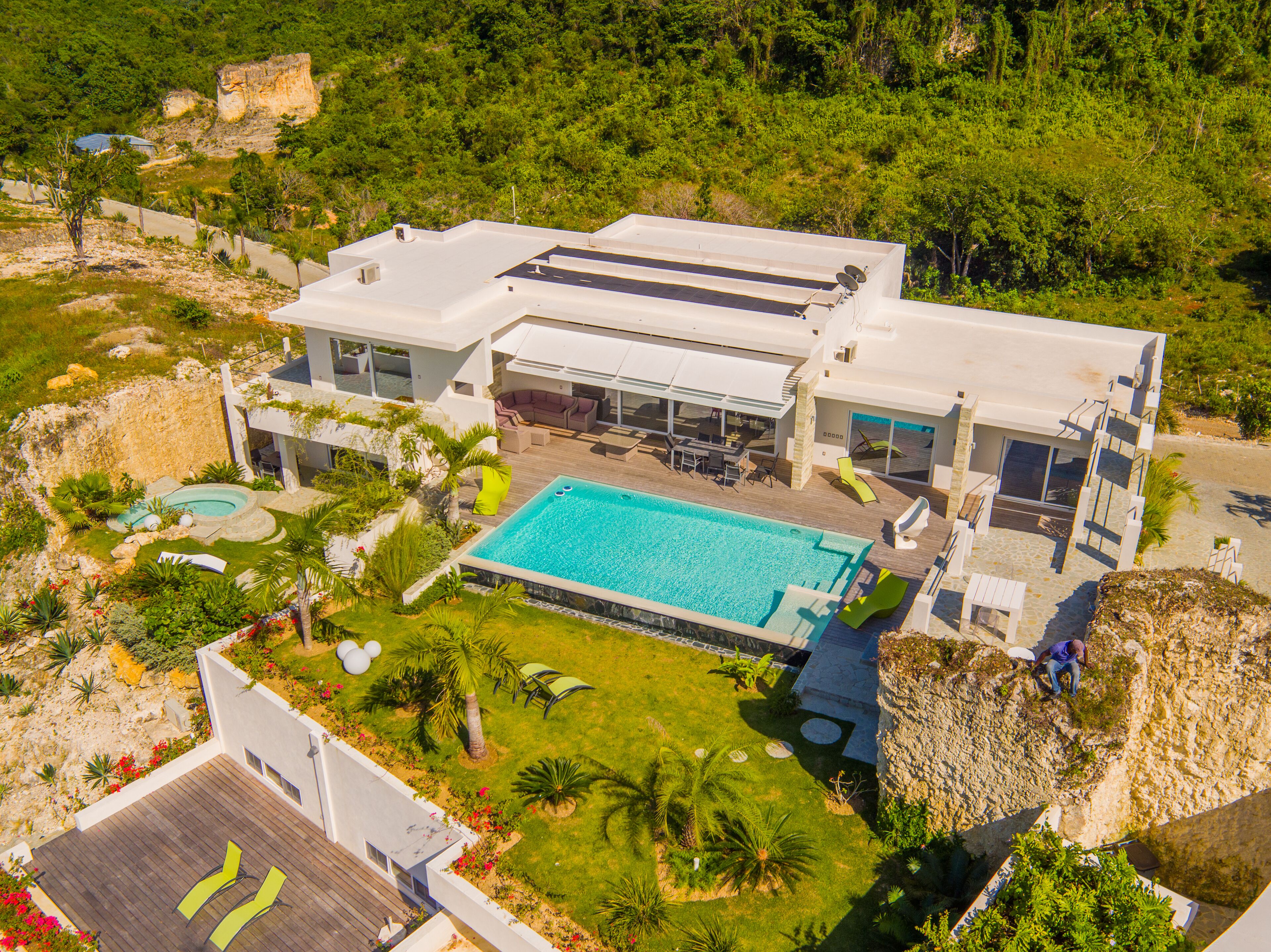 A modern house with a swimming pool, outdoor furniture, and lush landscaping.