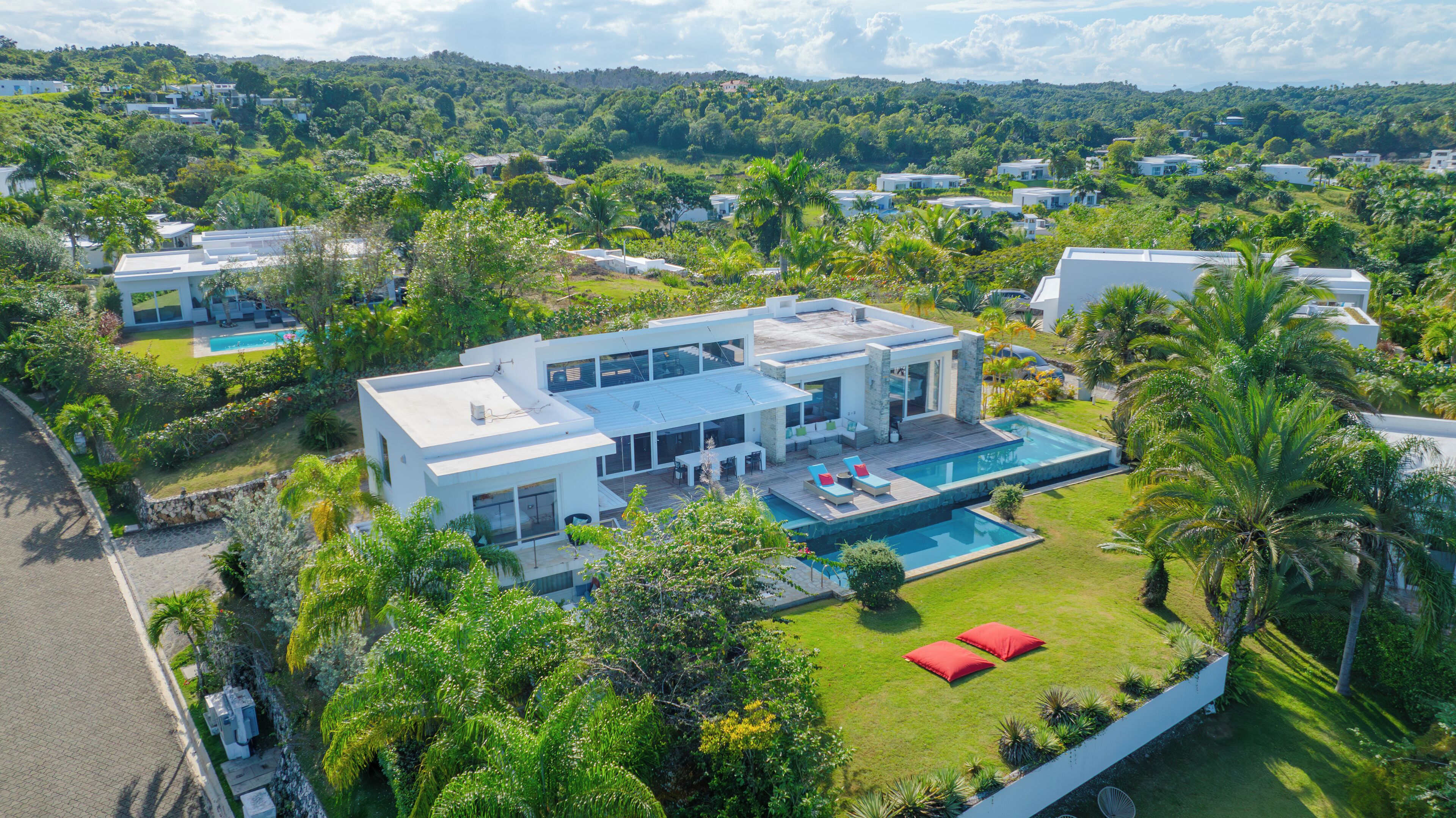 Una casa moderna con piscina, immersa nel verde e circondata da altre abitazioni.