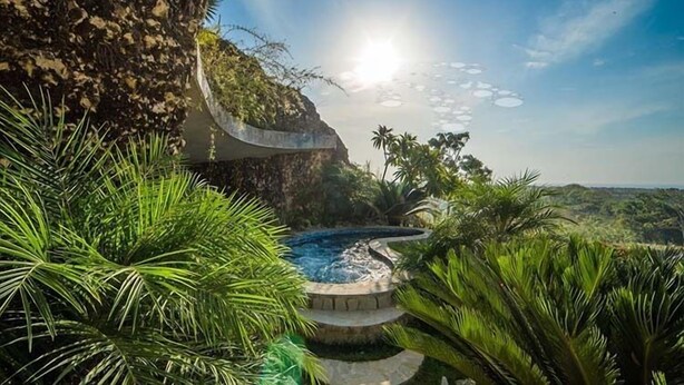 A hot tub surrounded by lush greenery and a cliffside. - Villas Agua Dulce (Cabarete)
