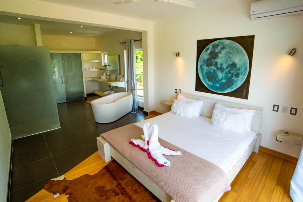 Une chambre d’hôtel moderne dotée d’un grand lit, d’une salle de bain avec baignoire et d’un coin repas.