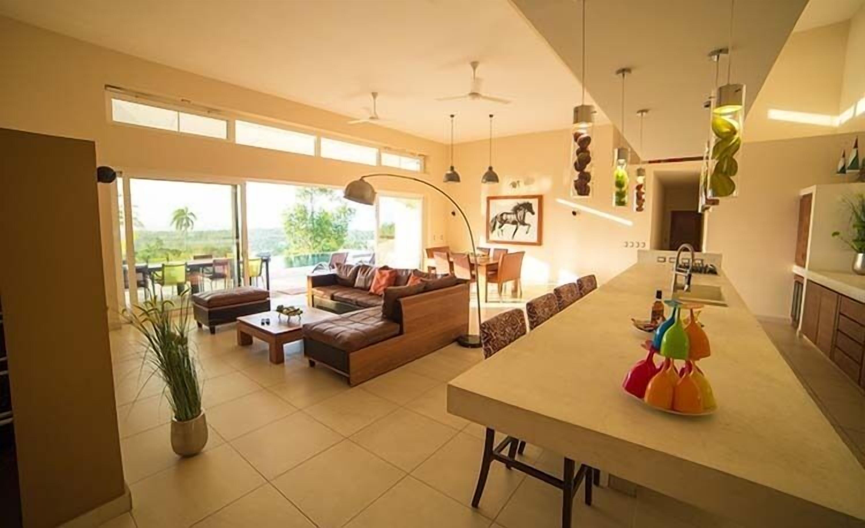 A spacious living area with a large sofa, a dining table, and a kitchen area with a central island.