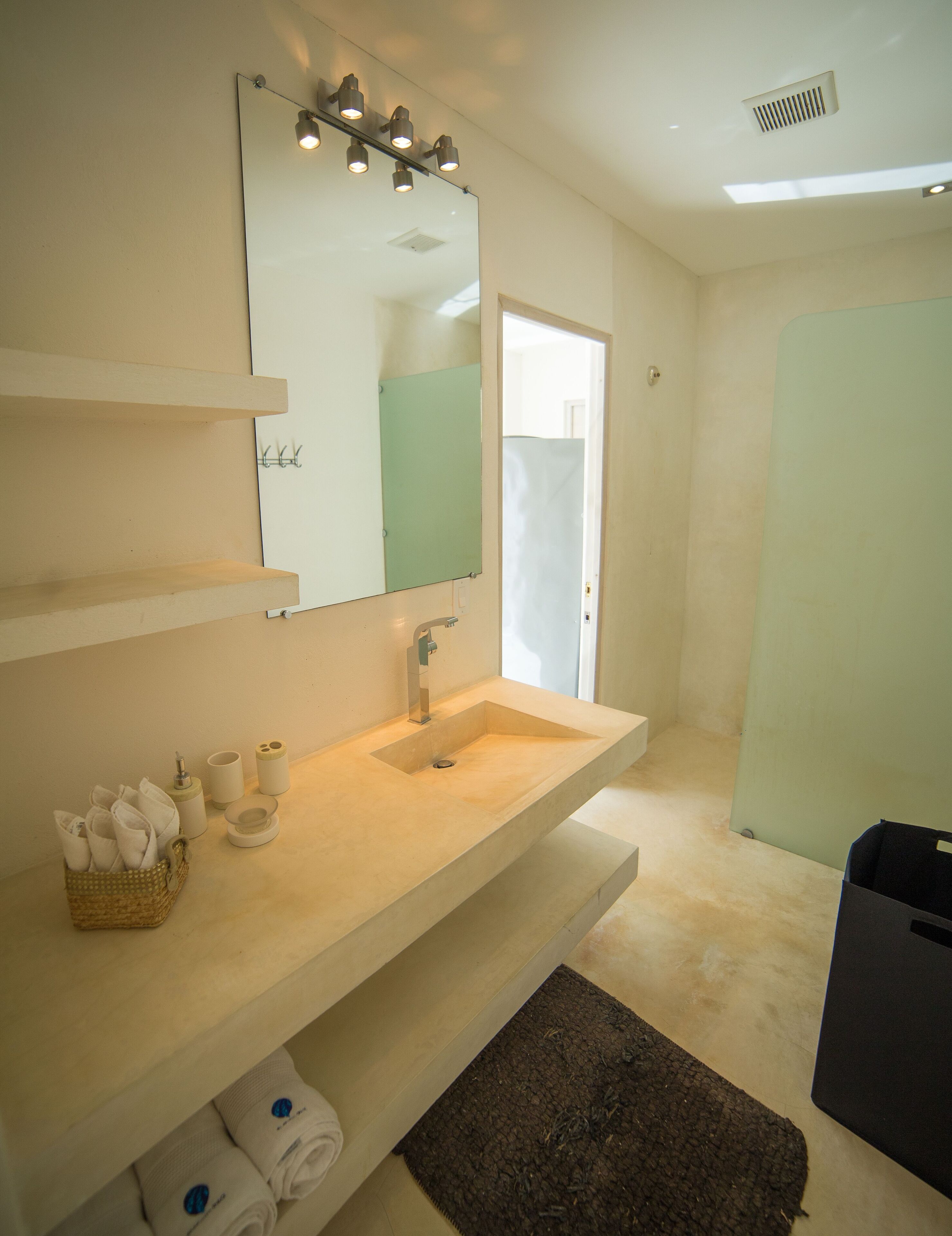 Een moderne badkamer met een grote spiegel, een beige wastafel en een douchegedeelte.