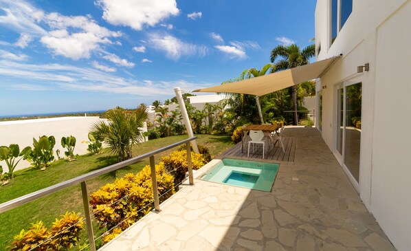 A balcony with a pool, outdoor furniture, and a view of the ocean. - Villas Agua Dulce - Loft Corazon (Sosúa)