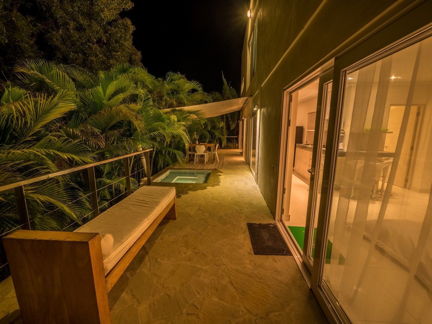 Ein überdachter Außenbereich mit Pool, Holzterrasse und Glastüren zu einem Raum.