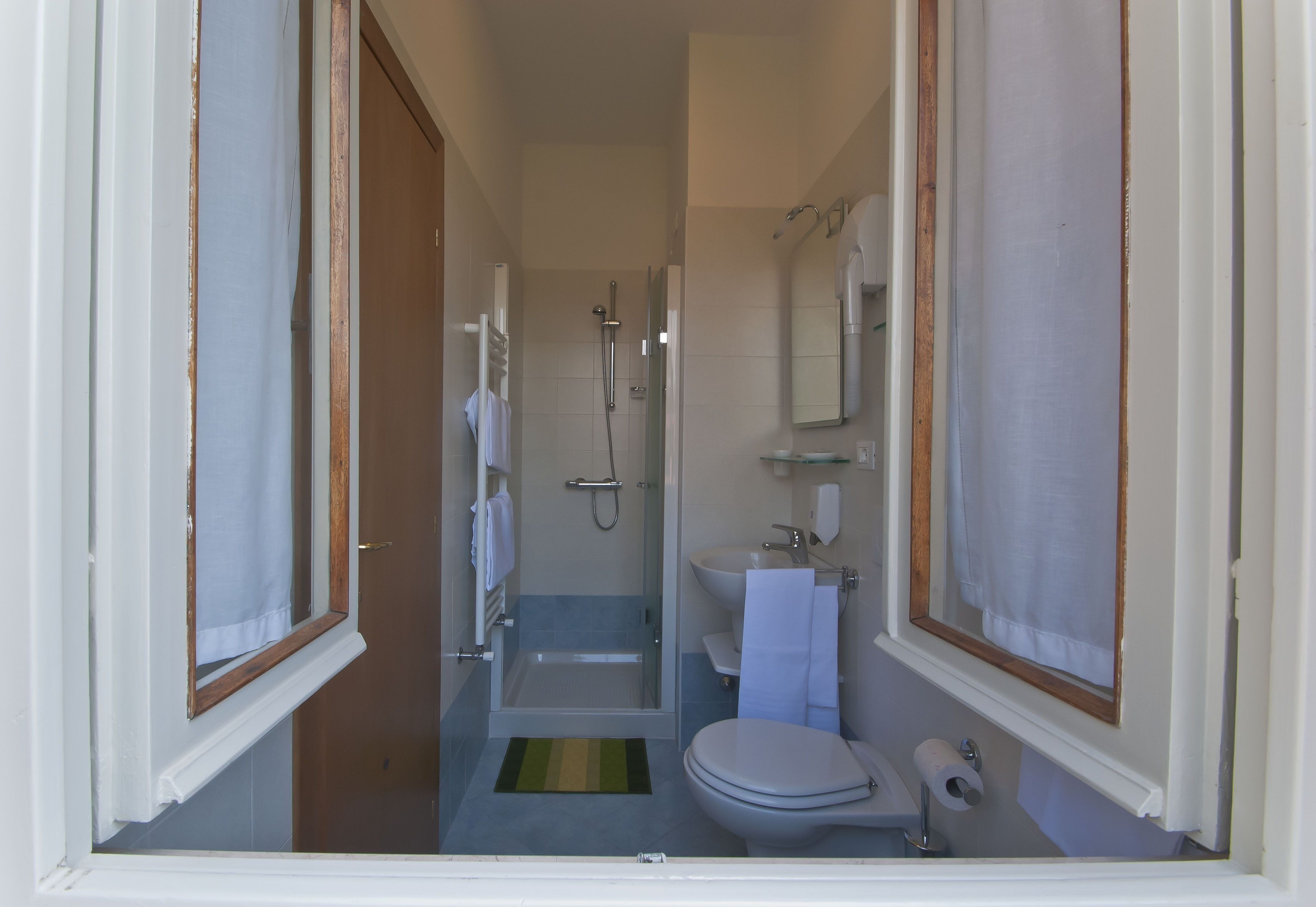 Un bagno con doccia, WC, lavandino e porta asciugamani.