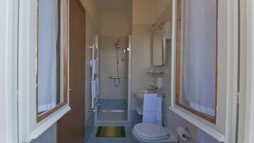 Un bagno con doccia, WC, lavandino e porta asciugamani.