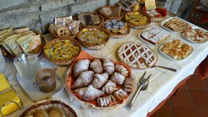 A table with various baked goods and pastries, including croissants, bread, and pies, arranged on a white tablecloth. - Hotel Versilia (Camaiore)