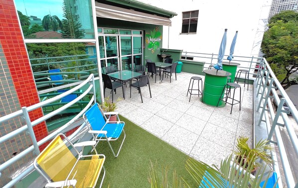 A rooftop terrace with outdoor seating, a small bar area, and a view of the surrounding buildings. - Br Hostel (Belo Horizonte)