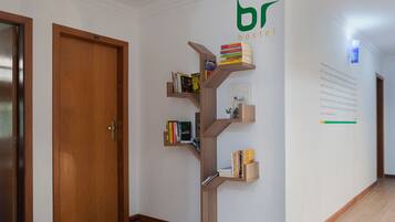 Un couloir avec une bibliothèque en bois adossée au mur, une porte en bois et un mur orné d’un logo et d’un texte.