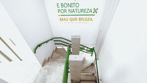 A staircase with green handrails and a white wall with a sign that reads "E BONITO POR NATUREZA, MAS DI BELEZA." - Br Hostel (Belo Horizonte)