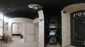 A modern interior with stone walls, a blackboard with writing, and a sign indicating an exit. - Br Hostel (Belo Horizonte)