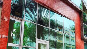 A building with large windows reflecting trees and parked cars. - Br Hostel (Belo Horizonte)