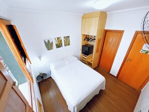 A bedroom with a bed, a wardrobe, a desk with a computer, and a small plant. - Br Hostel (Belo Horizonte)