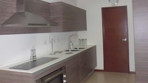 A modern kitchen with a built-in oven, stainless steel sink, and a large range hood.