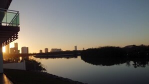A serene lakeside view with a modern building and a glass bridge overlooking the water.