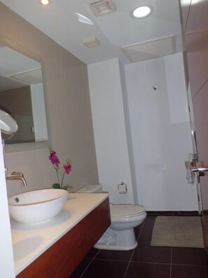Un baño moderno con un lavabo blanco, un inodoro y una zona de ducha.