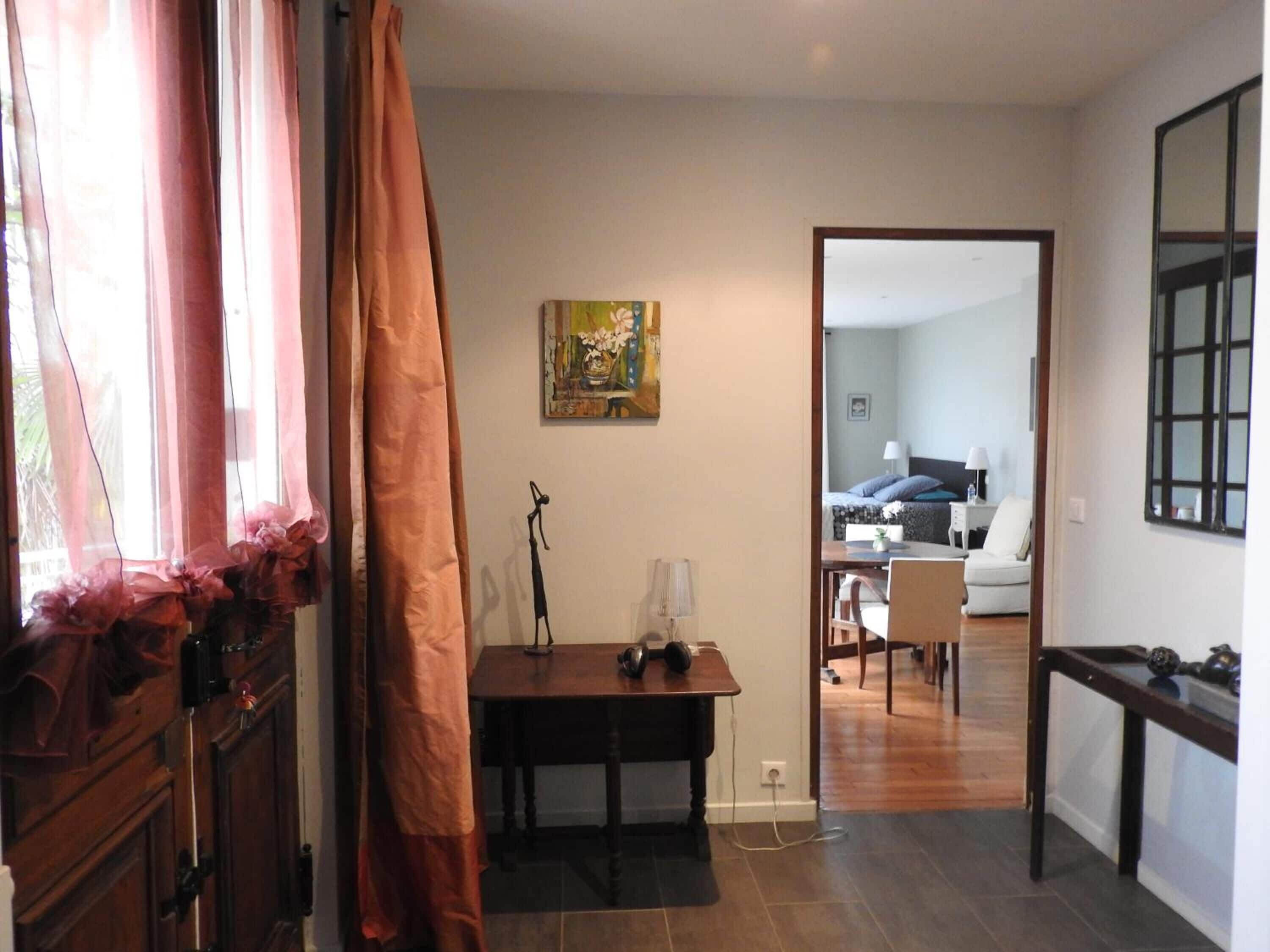 Een kamer met een eettafel, een stoel, een bijzettafeltje met een lamp en een schilderij aan de muur.