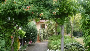 A garden pathway leading to a building, surrounded by lush greenery and flowering plants. - Chambre d'hôte La Bacotterie (Bois-le-Roi)
