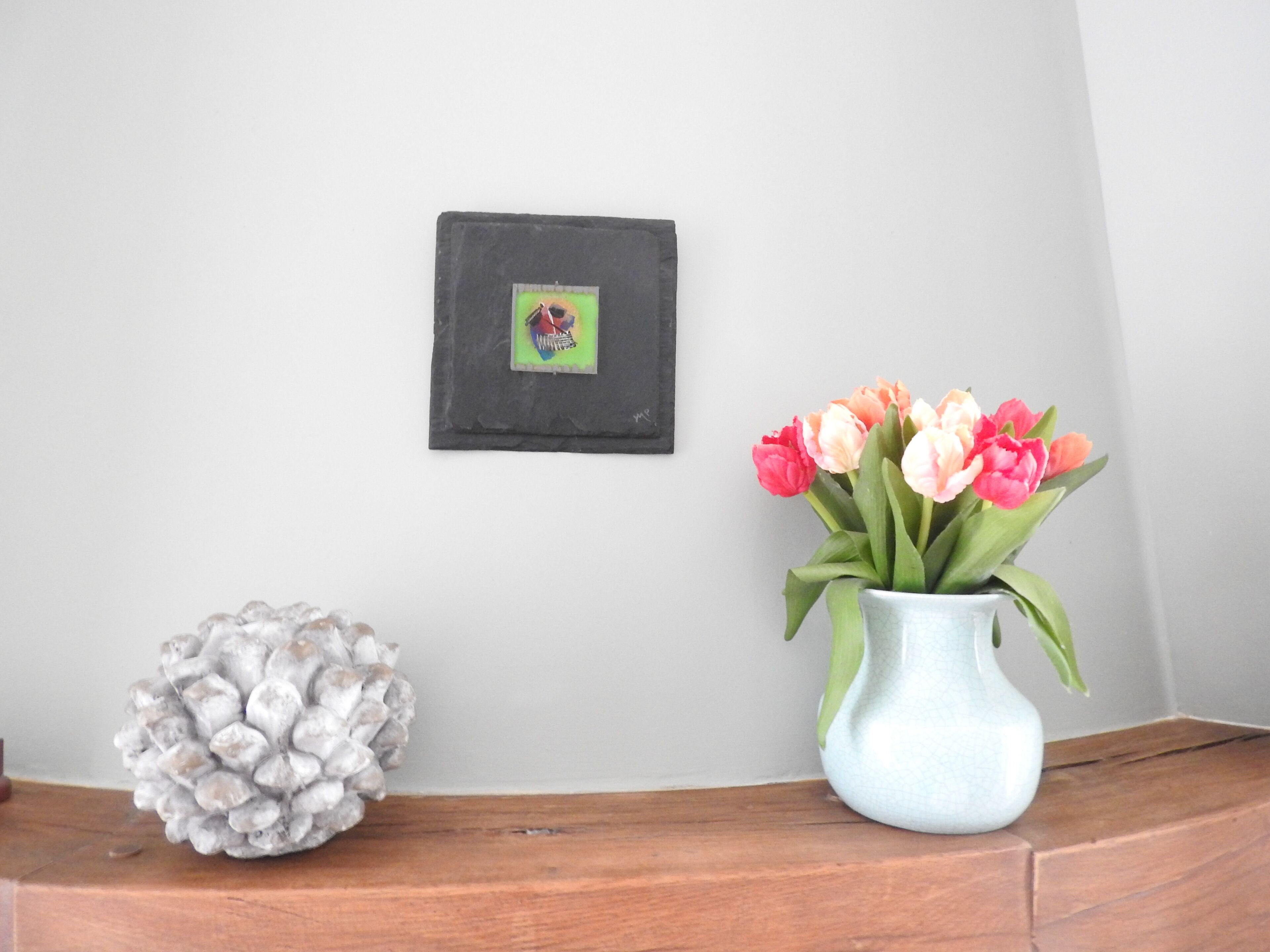 A wooden shelf with a vase of tulips and a decorative object.