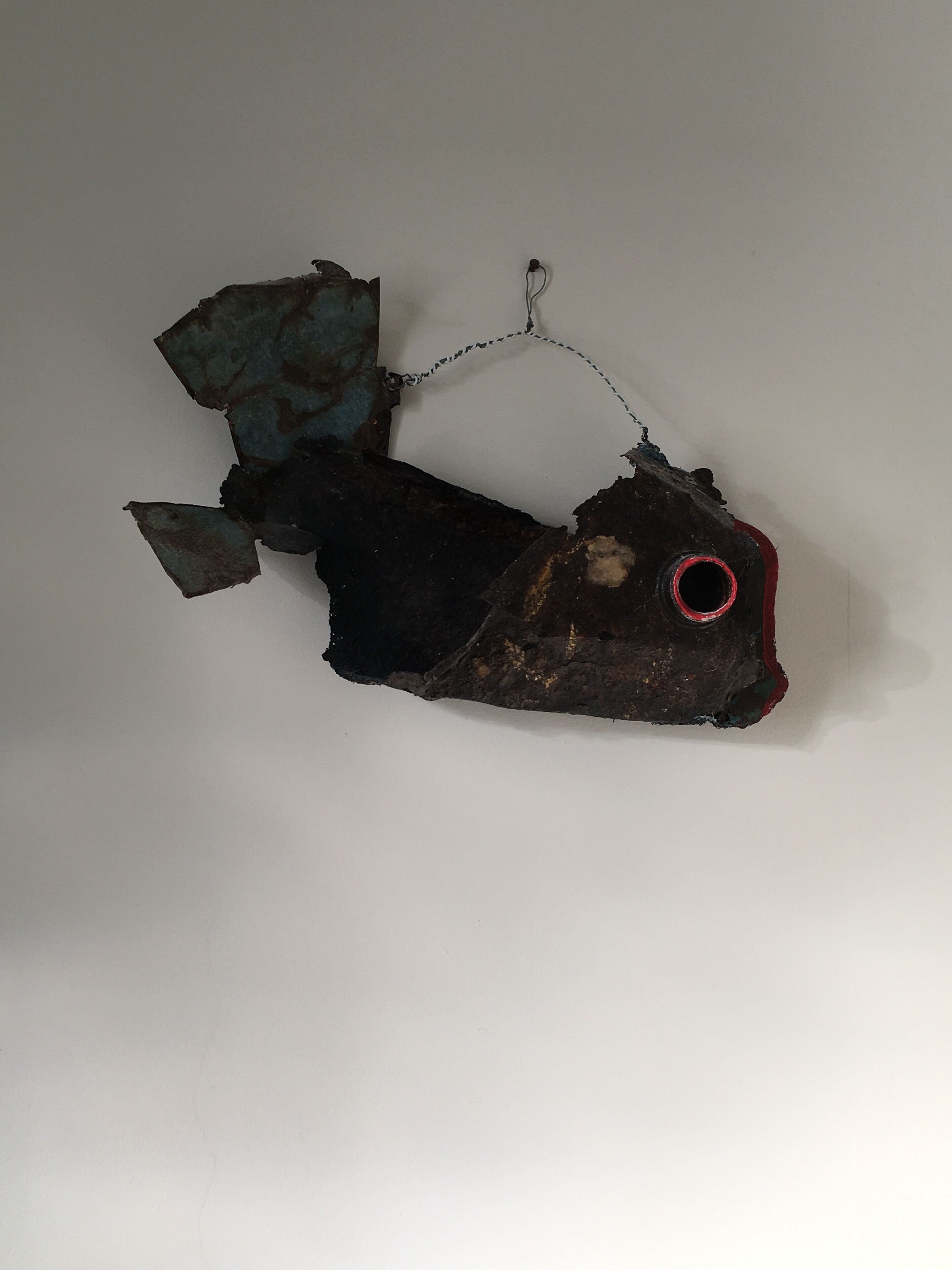 Un objet en forme de poisson, doté d’un œil rouge et d’une chaîne.
