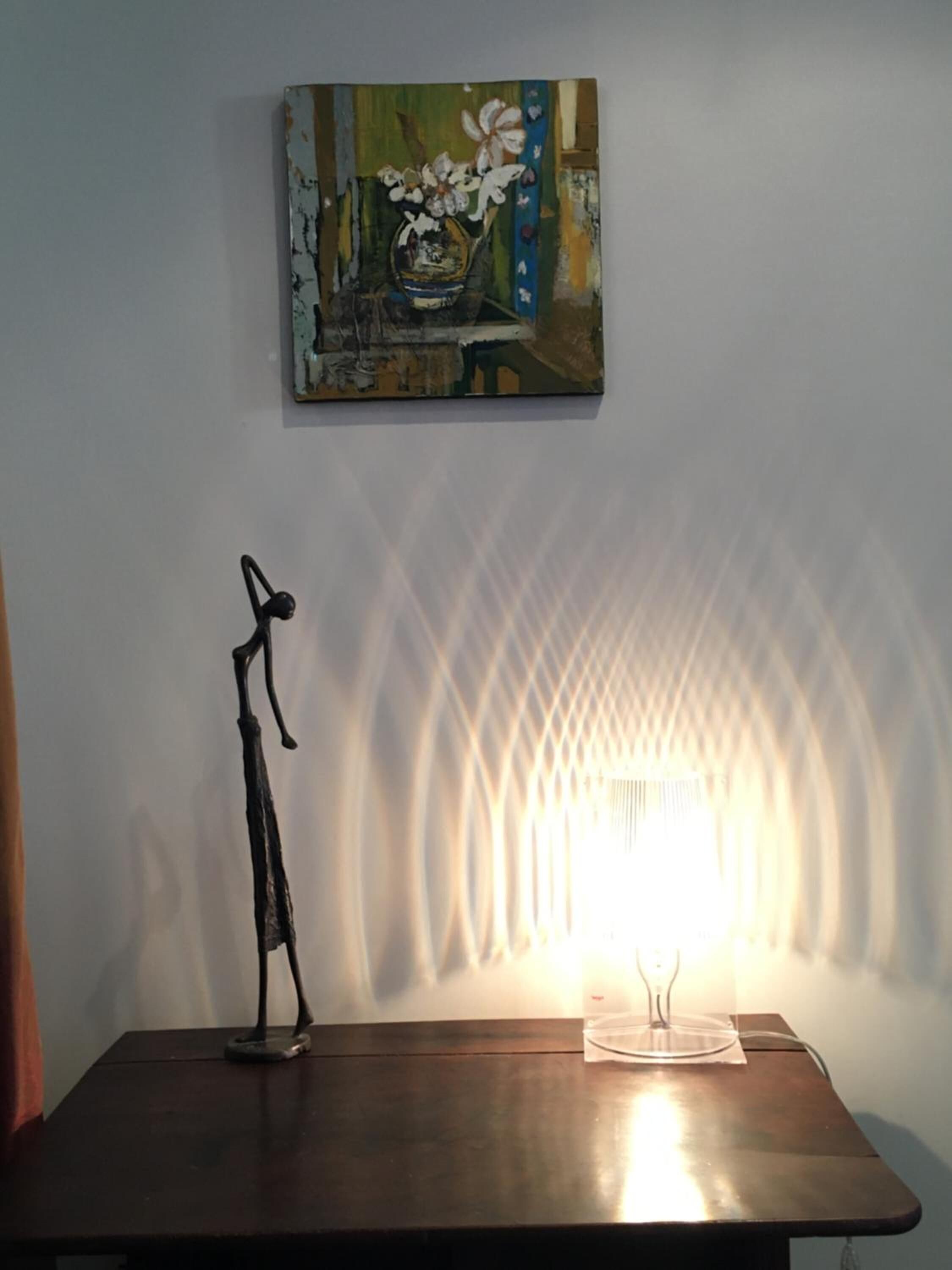 Une pièce avec une table, une lampe et un tableau au mur.