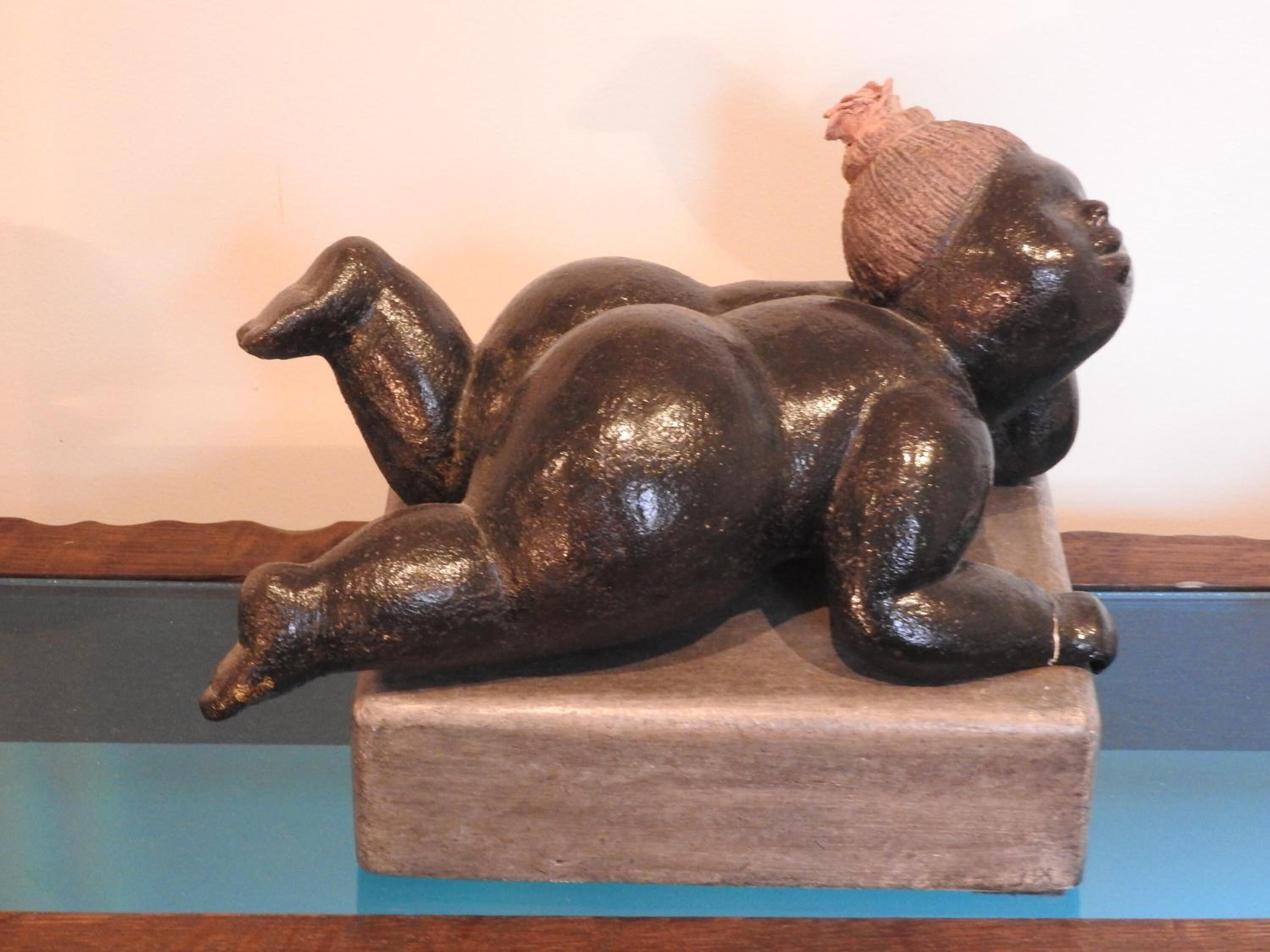 Eine Skulptur einer liegenden Figur auf einem Sockel.