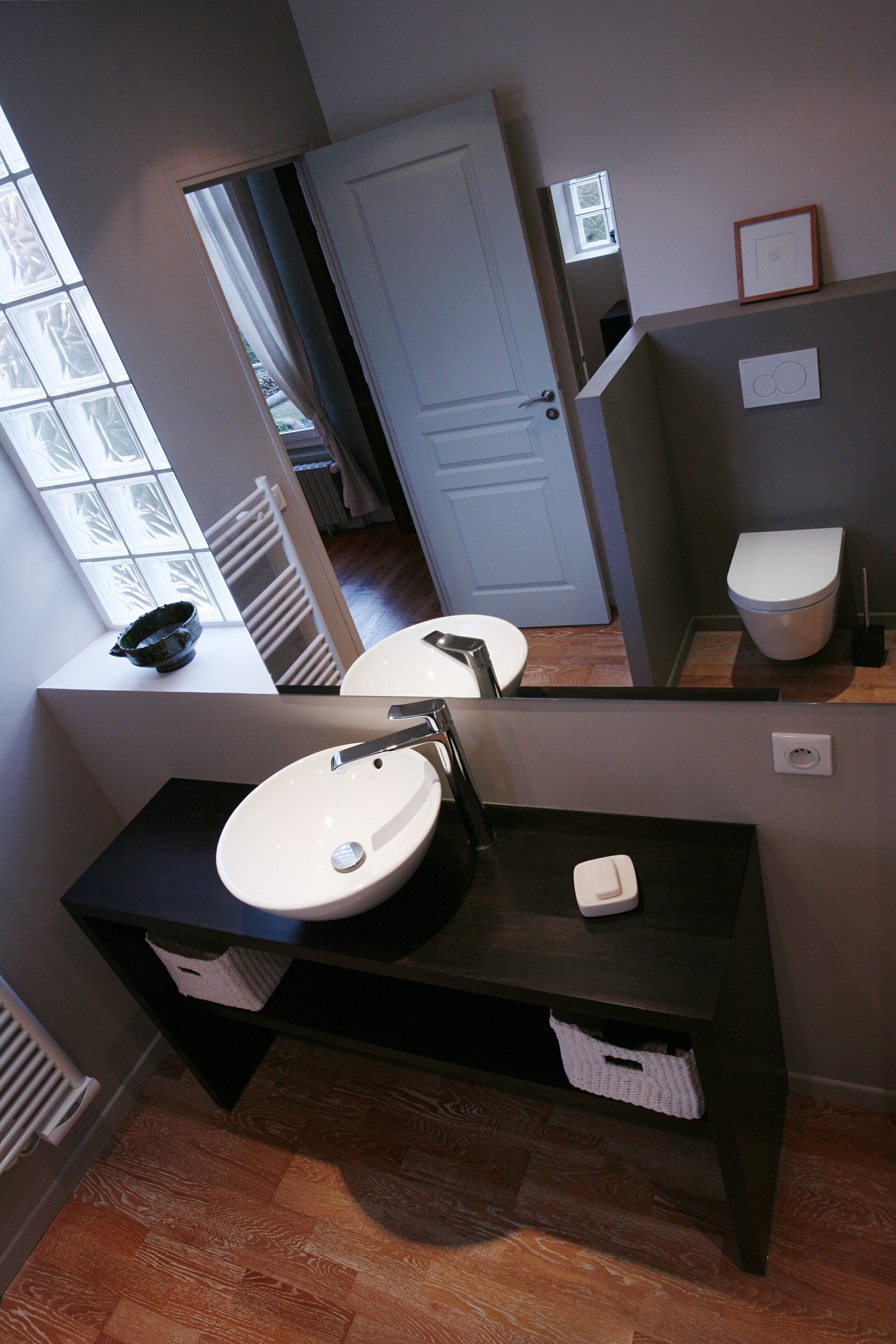Un baño moderno con un espejo grande, un lavabo blanco y un inodoro.