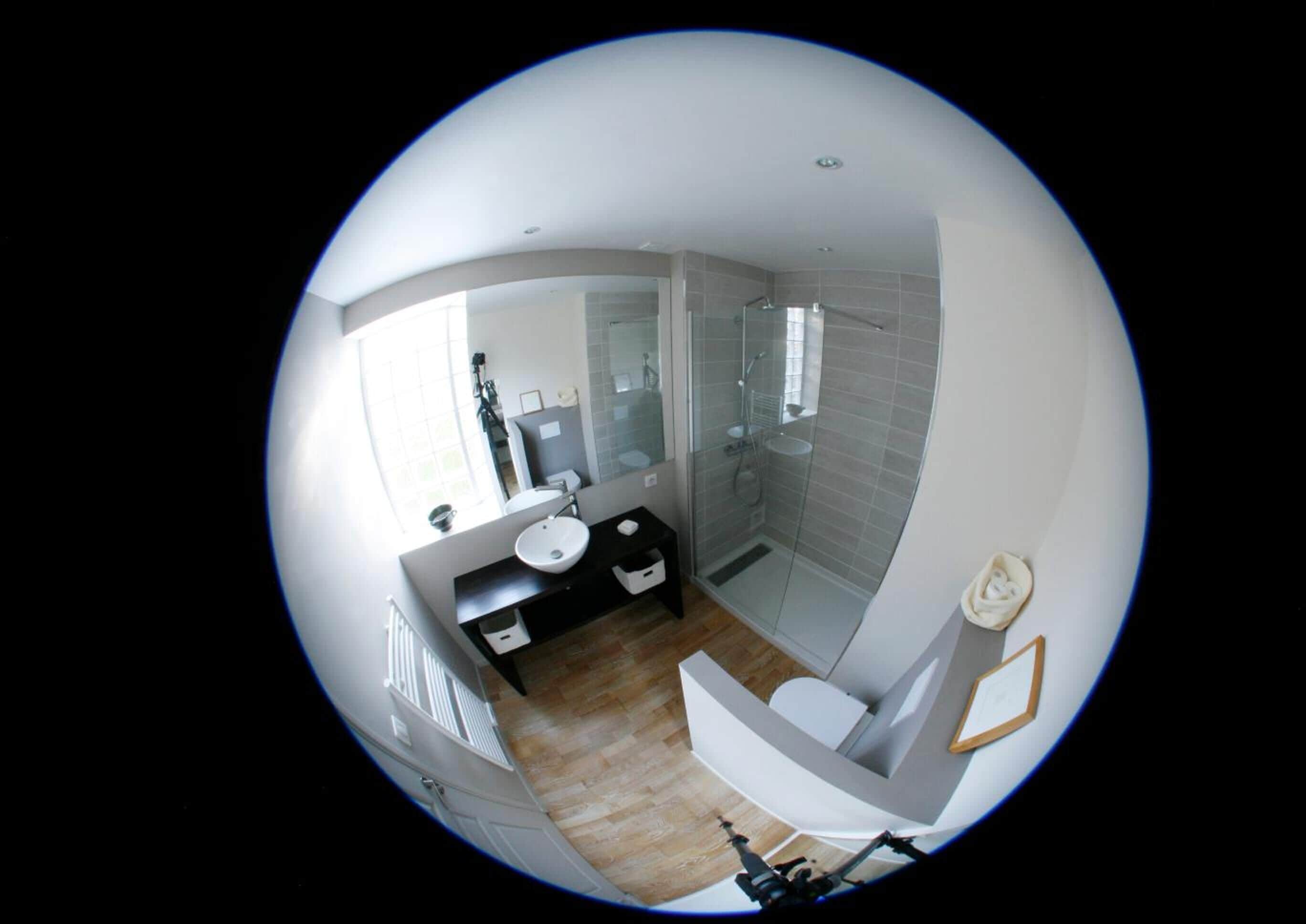 Un baño moderno con cabina de ducha de vidrio, un lavabo blanco y un inodoro.