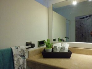 A bathroom with a bathtub, a towel rack, a potted plant, and a mirror. - Casa - Condo (Mazatlán)