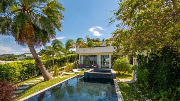 A swimming pool with lounge chairs and inflatable rings, surrounded by lush greenery and palm trees. - Villas Agua Dulce - Villa Eden (Sosúa)