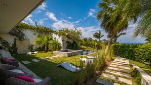 A well-maintained outdoor patio area with a stone pool, lounge chairs, and a stone pathway leading to a grassy lawn. - Villas Agua Dulce - Villa Eden (Sosúa)