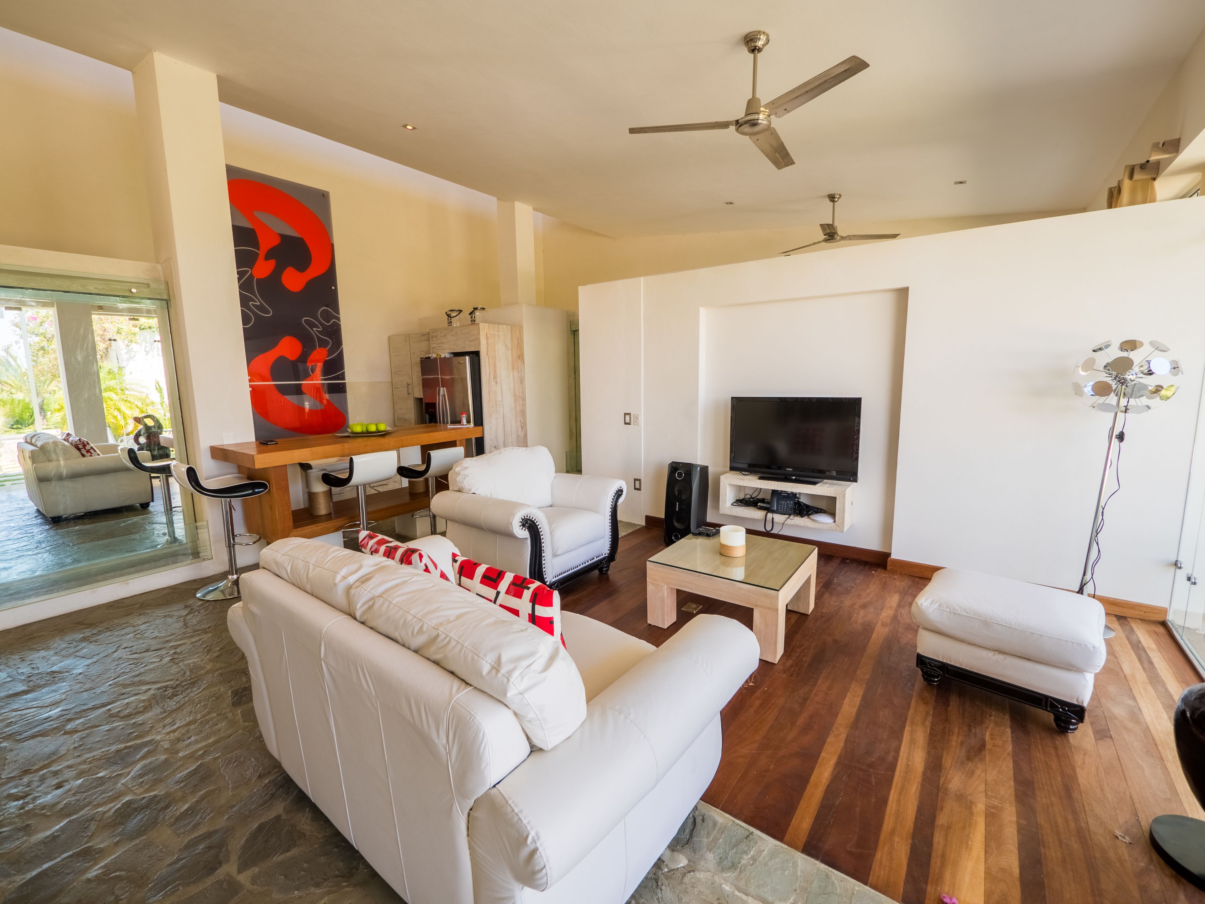 A modern living room with a sofa, a coffee table, a TV, and a dining area with chairs and a table.