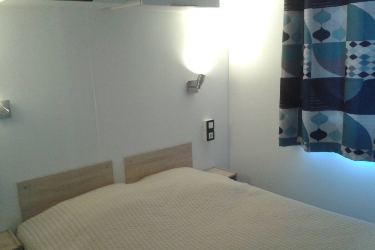 A single bed with a wooden headboard, a bedside table, and a wall-mounted light.