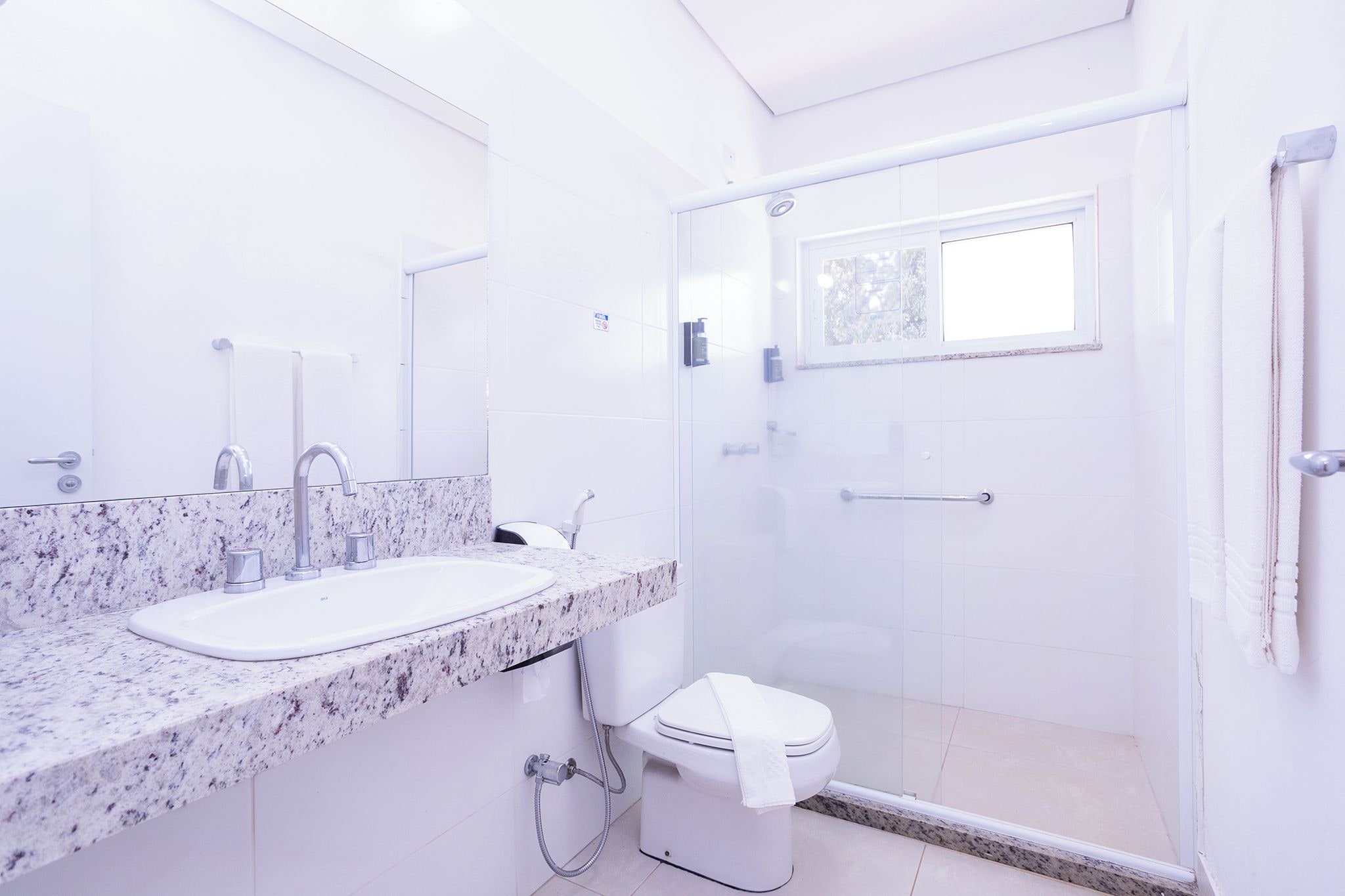 A modern bathroom with a marble sink, a glass shower enclosure, and a toilet.