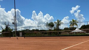 Un court de tennis avec un filet, deux raquettes de tennis et trois balles de tennis.