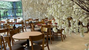 A restaurant with round tables and chairs, a stone wall, and white floral decorations. - Vale das Águas Fazenda Resort (Aguas de Santa Barbara)