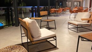 An outdoor seating area with modern furniture and a view of the pool. - Vale das Águas Fazenda Resort (Aguas de Santa Barbara)