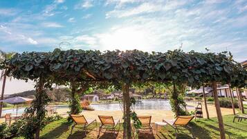 A covered outdoor seating area with chairs and a pool in the background.